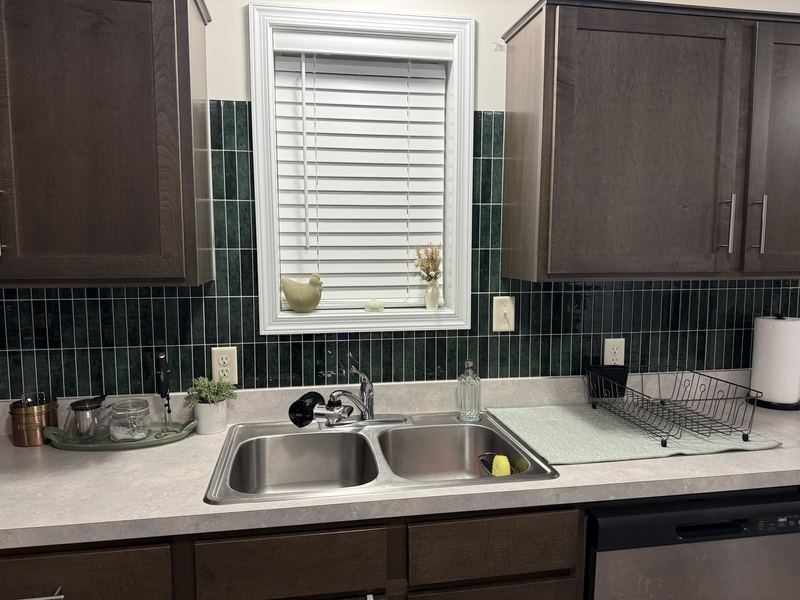 Sink wall after, with green tile around the window